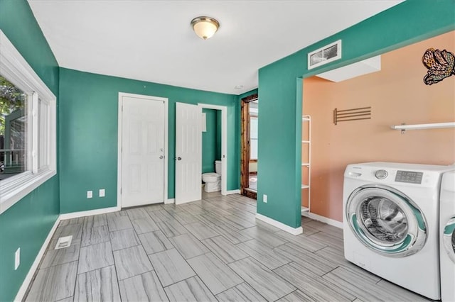 clothes washing area with laundry area, washing machine and dryer, visible vents, and baseboards