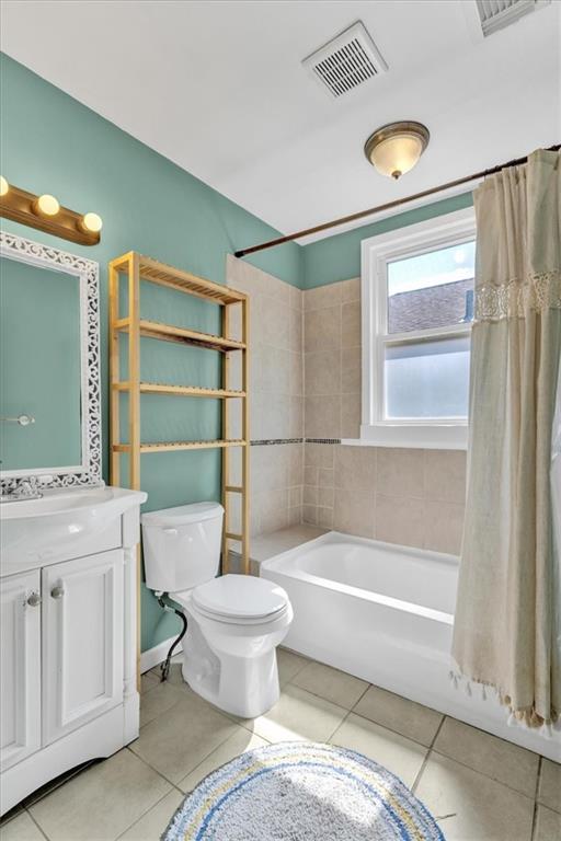 bathroom with vanity, visible vents, shower / tub combo, tile patterned floors, and toilet