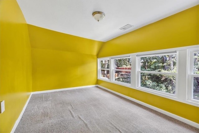 empty room with visible vents, baseboards, lofted ceiling, and carpet floors