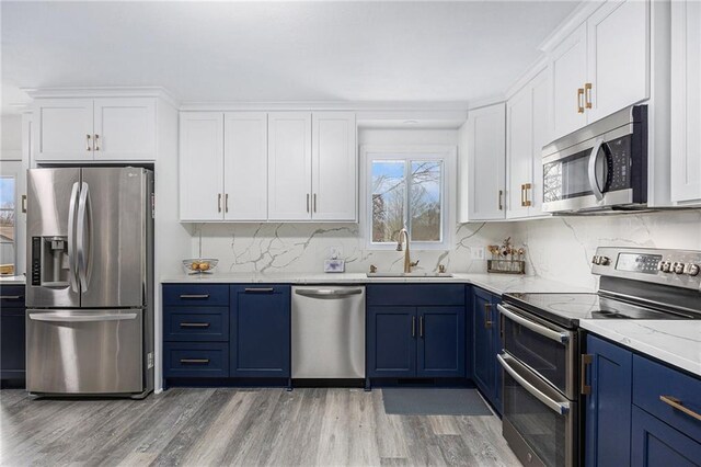 1008 Bristol Way, Liberty, MO 64068 - kitchen with light wood-style flooring, a sink, blue cabinetry, white cabinetry, and appliances with stainless steel finishes