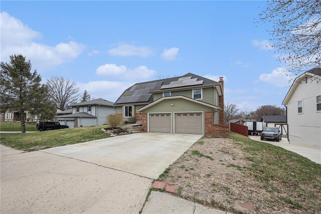 1008 Bristol Way, Liberty, MO 64068 - view of front of house with fence, concrete driveway, brick siding, solar panels, and a chimney