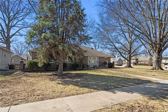 view of front of house featuring brick siding, a residential view, a front yard, and fence