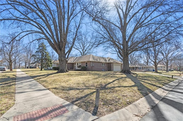 view of front of property featuring a front yard, an attached garage, brick siding, and a residential view