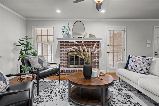 living area with a wealth of natural light, wood finished floors, a brick fireplace, and ornamental molding