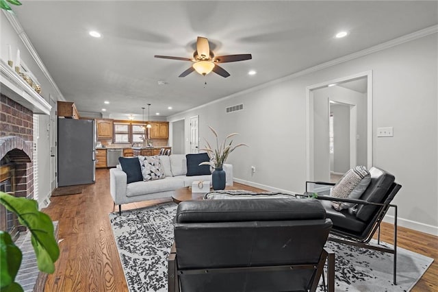 living room with wood finished floors, a fireplace, and ornamental molding