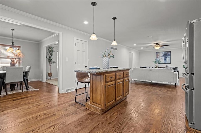 kitchen with visible vents, brown cabinets, freestanding refrigerator, and dark wood-type flooring