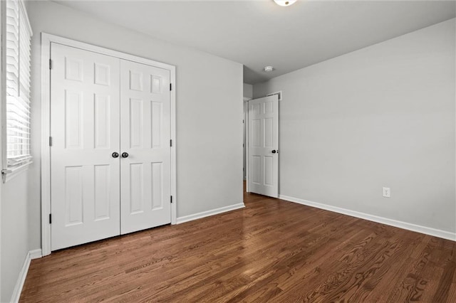 unfurnished bedroom with a closet, baseboards, and wood finished floors