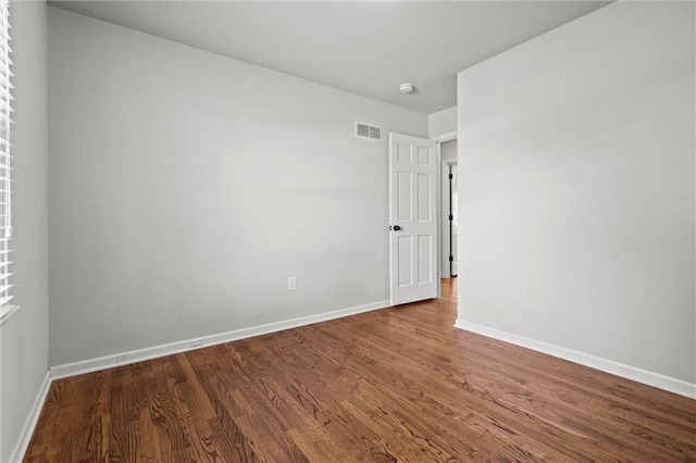 spare room with visible vents, baseboards, and wood finished floors