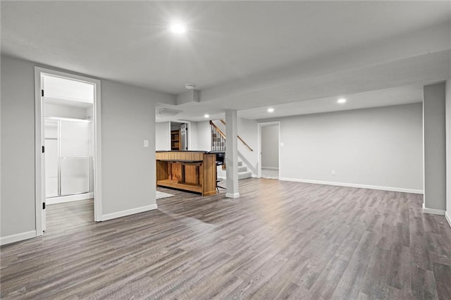 unfurnished living room featuring recessed lighting, stairway, baseboards, and dark wood finished floors