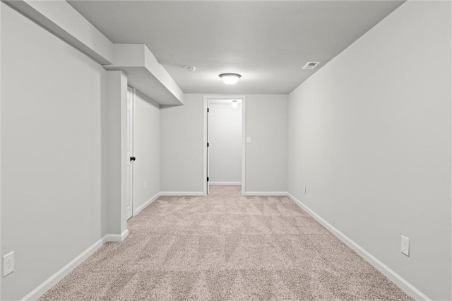 finished below grade area featuring visible vents, carpet, and baseboards