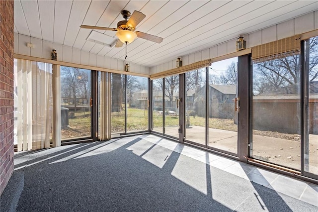 unfurnished sunroom with a residential view, wood ceiling, and ceiling fan