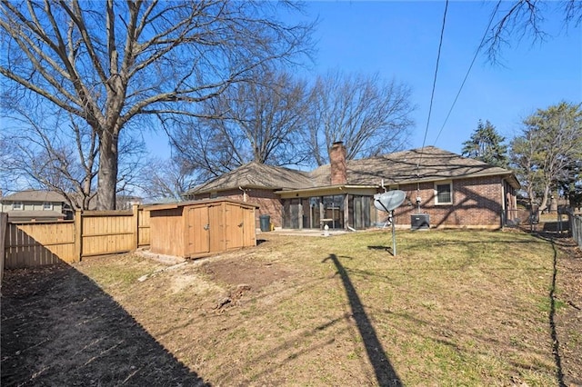 rear view of house with a shed, fence, an outdoor structure, brick siding, and a chimney