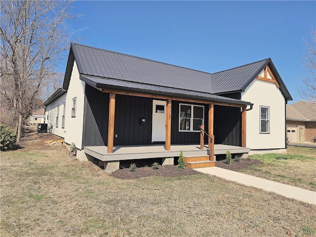 modern farmhouse style home with metal roof, a porch, cooling unit, and a front lawn