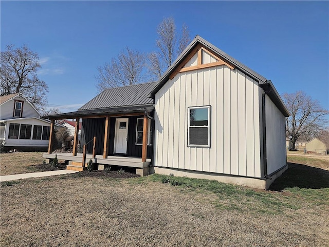 view of front facade featuring board and batten siding, a front yard, covered porch, metal roof, and a standing seam roof