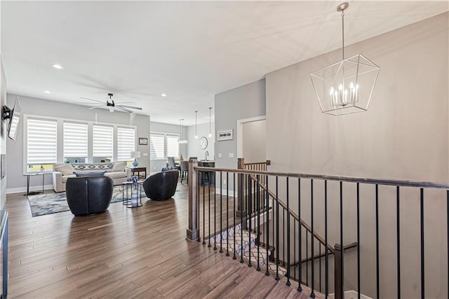 hall with wood finished floors, baseboards, recessed lighting, a notable chandelier, and an upstairs landing