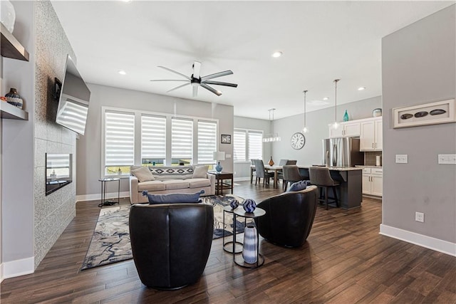 living room with baseboards, dark wood-type flooring, and a ceiling fan