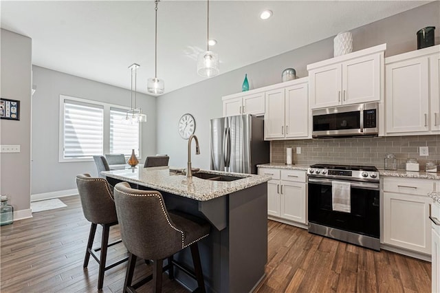 kitchen featuring backsplash, appliances with stainless steel finishes, a breakfast bar, and dark wood-style flooring