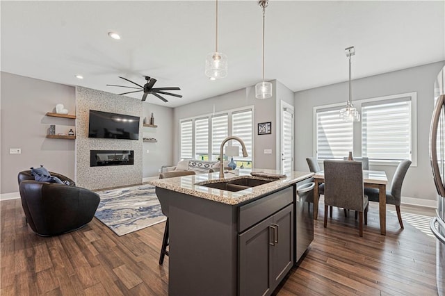 kitchen featuring open floor plan, ceiling fan with notable chandelier, dark wood-style flooring, and a sink