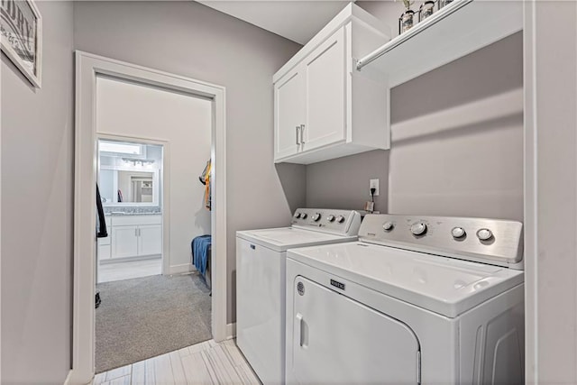 washroom with washing machine and dryer, cabinet space, light colored carpet, and baseboards