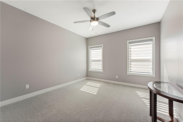 carpeted empty room featuring ceiling fan and baseboards