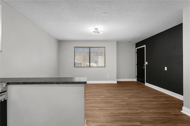 empty room featuring a textured ceiling, baseboards, and wood finished floors