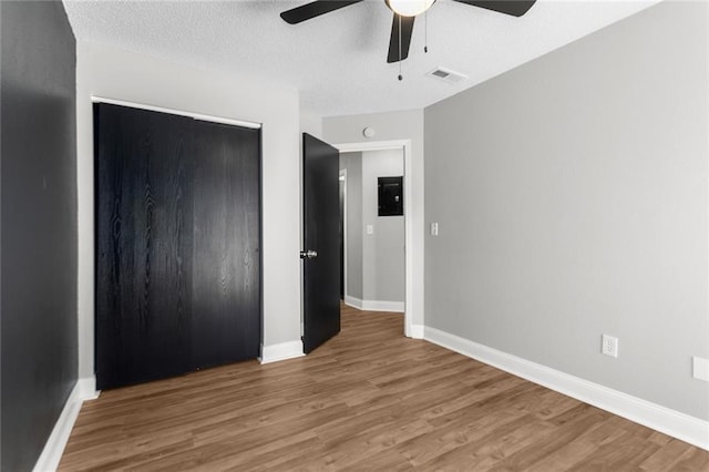 unfurnished bedroom with a closet, baseboards, a textured ceiling, and wood finished floors