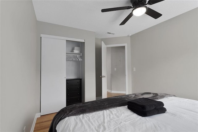 bedroom with visible vents, wood finished floors, a closet, baseboards, and ceiling fan