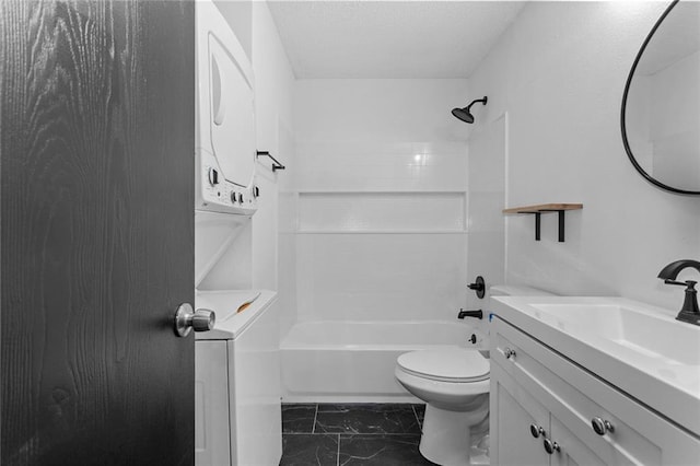 bathroom featuring vanity, shower / bathing tub combination, stacked washer / dryer, toilet, and marble finish floor