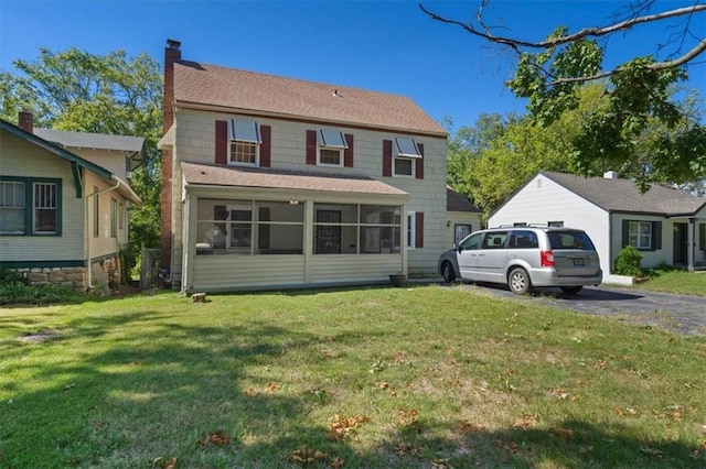 rear view of property with a lawn, a chimney, and a sunroom