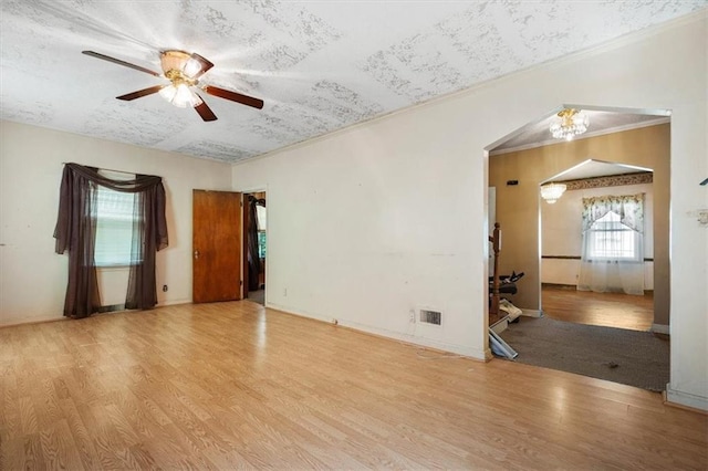 unfurnished room with ceiling fan, arched walkways, wood finished floors, and ornamental molding