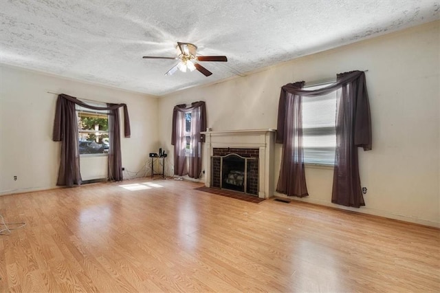 unfurnished living room with a textured ceiling, a fireplace with flush hearth, wood finished floors, and ceiling fan