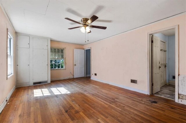 unfurnished bedroom with visible vents, ensuite bathroom, baseboards, and hardwood / wood-style flooring