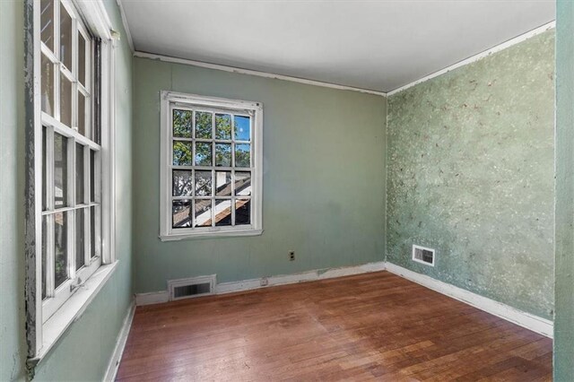 spare room featuring visible vents, ornamental molding, and wood finished floors