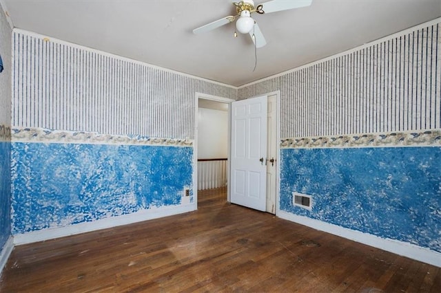 empty room featuring visible vents, wallpapered walls, baseboards, hardwood / wood-style flooring, and a ceiling fan