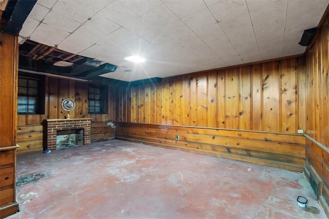 interior space featuring a brick fireplace, wooden walls, and concrete floors