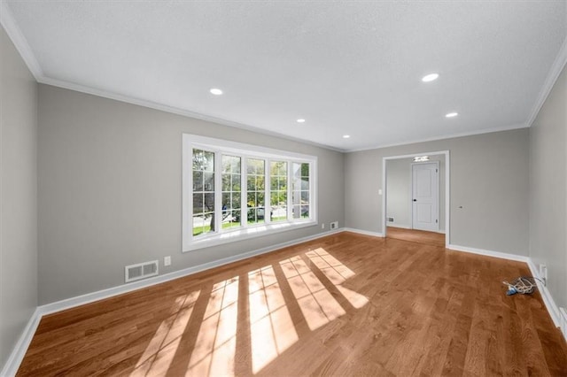 spare room featuring wood finished floors, visible vents, baseboards, recessed lighting, and ornamental molding