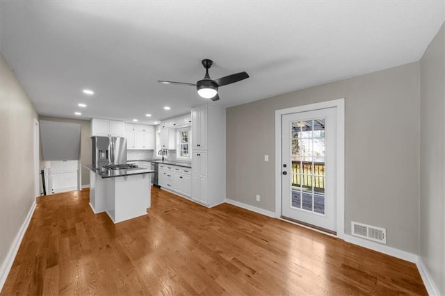 kitchen featuring visible vents, wood finished floors, white cabinetry, stainless steel fridge with ice dispenser, and baseboards