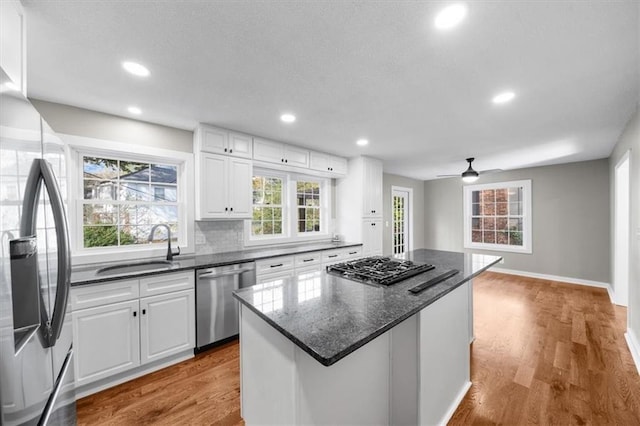 kitchen with light wood-style floors, a kitchen island, appliances with stainless steel finishes, and a sink