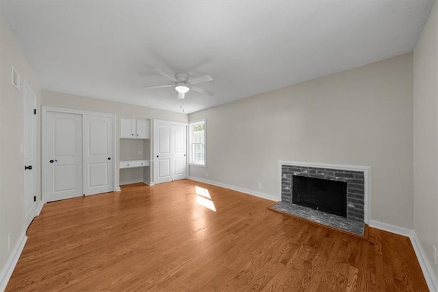 unfurnished living room with baseboards, ceiling fan, a fireplace, and light wood finished floors