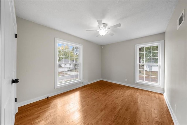 unfurnished room featuring visible vents, ceiling fan, baseboards, wood finished floors, and a textured ceiling