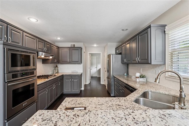 12109 Overbrook Ct, Leawood, KS 66209 - kitchen with stainless steel appliances, under cabinet range hood, decorative backsplash, dark wood-style flooring, and a textured ceiling