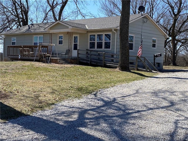 exterior space with a lawn, gravel driveway, and roof with shingles