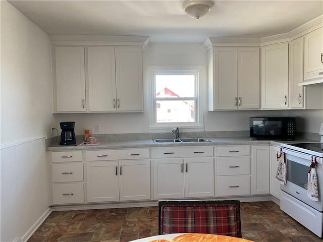 kitchen featuring stone finish flooring, black microwave, white cabinets, white electric range, and a sink