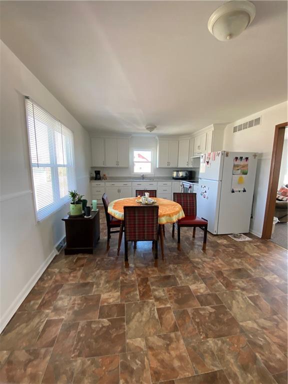 dining space with stone finish floor, plenty of natural light, baseboards, and visible vents