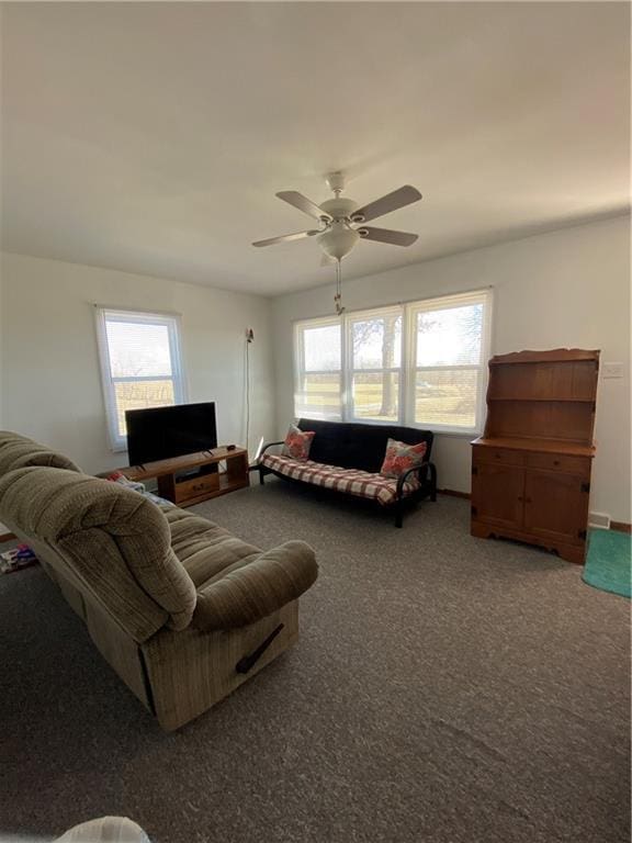 living area with a wealth of natural light, ceiling fan, and carpet flooring