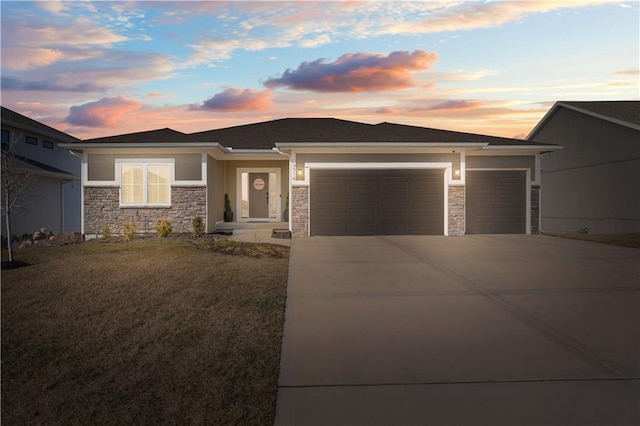 prairie-style house featuring a garage, stone siding, driveway, and stucco siding