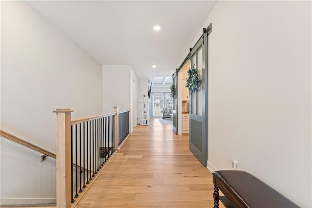 hall featuring an upstairs landing, recessed lighting, a barn door, light wood finished floors, and baseboards