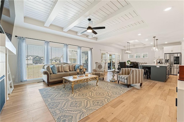 living room featuring light wood finished floors, beamed ceiling, ceiling fan with notable chandelier, and wooden ceiling