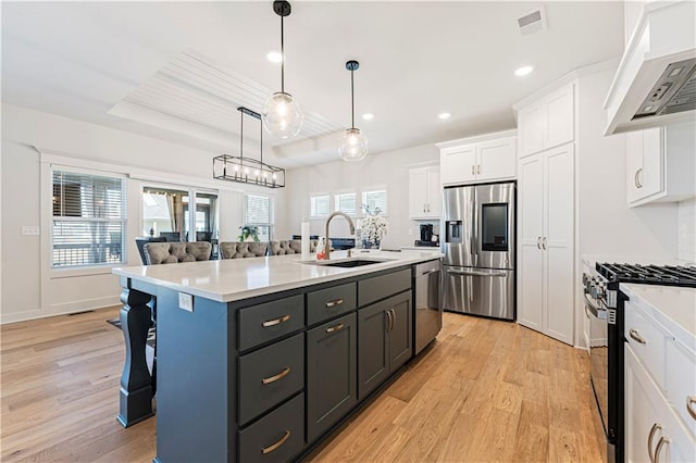 kitchen featuring a sink, white cabinetry, appliances with stainless steel finishes, a breakfast bar area, and wall chimney exhaust hood