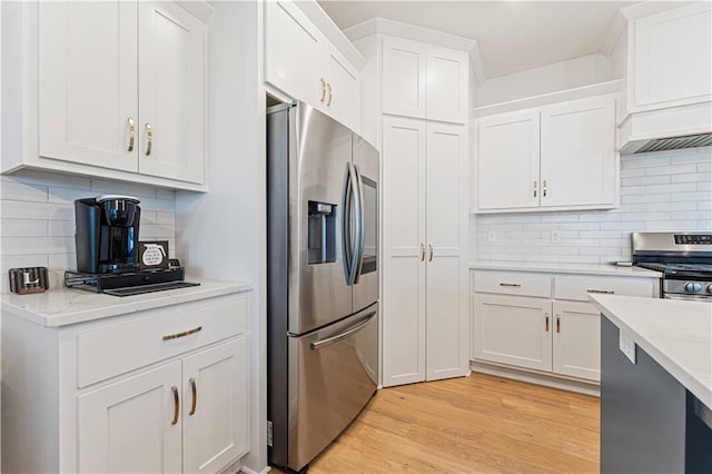 kitchen with light stone counters, stainless steel appliances, decorative backsplash, white cabinets, and light wood-type flooring